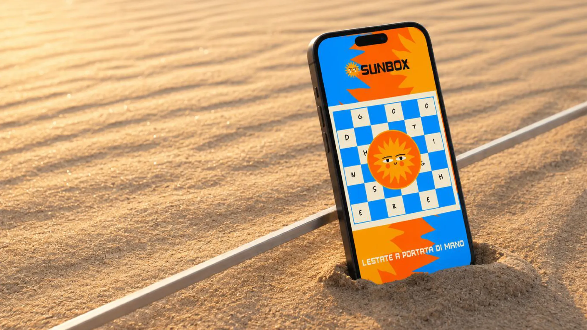 Uno smartphone con la grafica Sunbox infilato nella sabbia