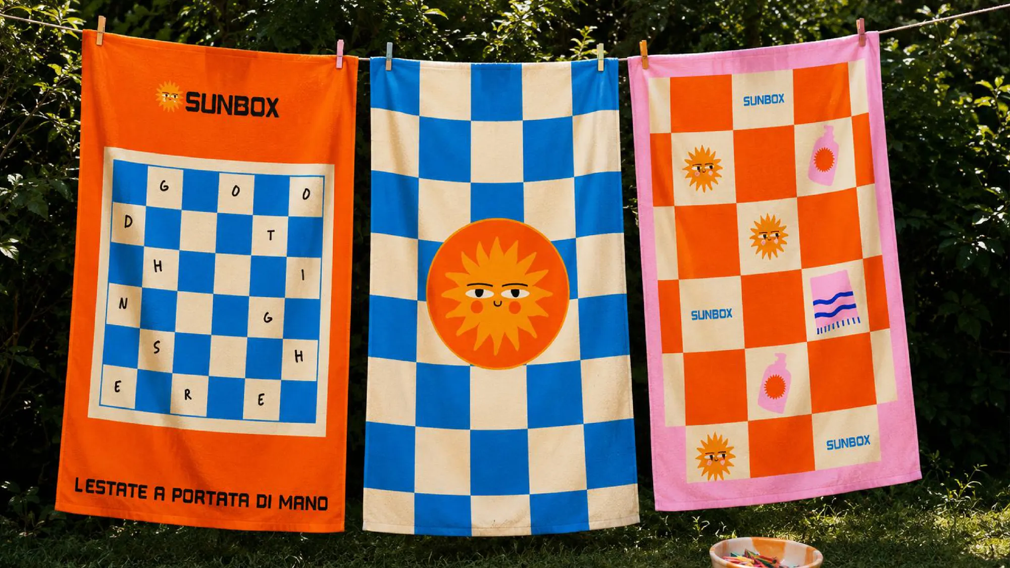 Tre teli mare Sunbox stesi su un filo in giardino