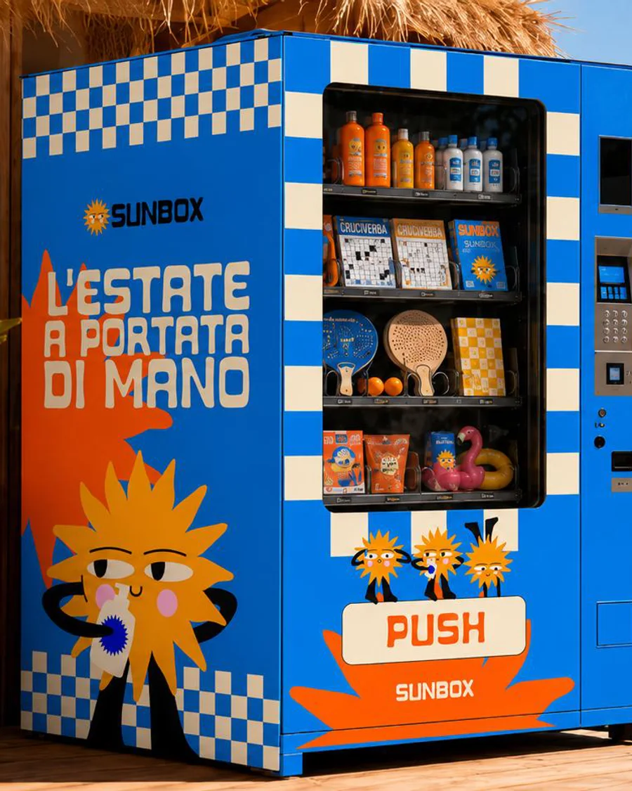 Distributore Sunbox blu con la scritta L’estate a portata di mano e Sunny, in uno stabilimento sul mare